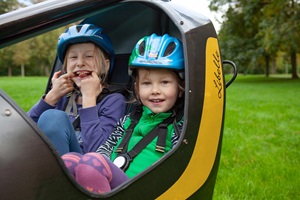 Zwei Kinder mit Schutzhelmen sitzen im Fahrrad